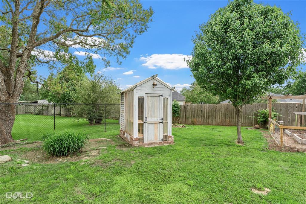 1962 Palmetto Road Benton, LA 71006 - Photo 32 of 40 The property features a spacious yard with a lawn, mature trees, a storage shed, and a fenced garden area