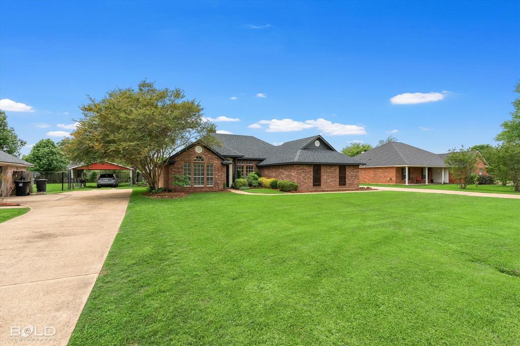1962 Palmetto Road Benton, LA 71006 - Photo 36 of 40 The property features a brick exterior, a well-maintained lawn, and a paved driveway leading to a carport
