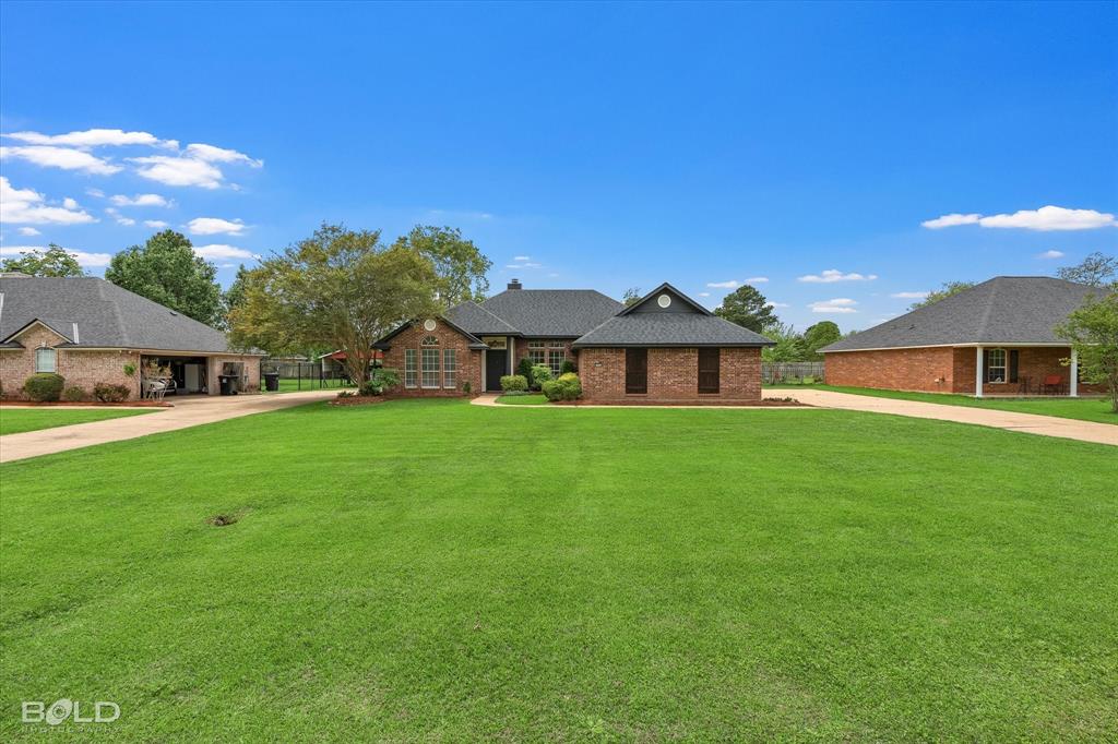 1962 Palmetto Road Benton, LA 71006 - Photo 38 of 40 The property features a brick exterior, a grey shingled roof, and an expansive green lawn
