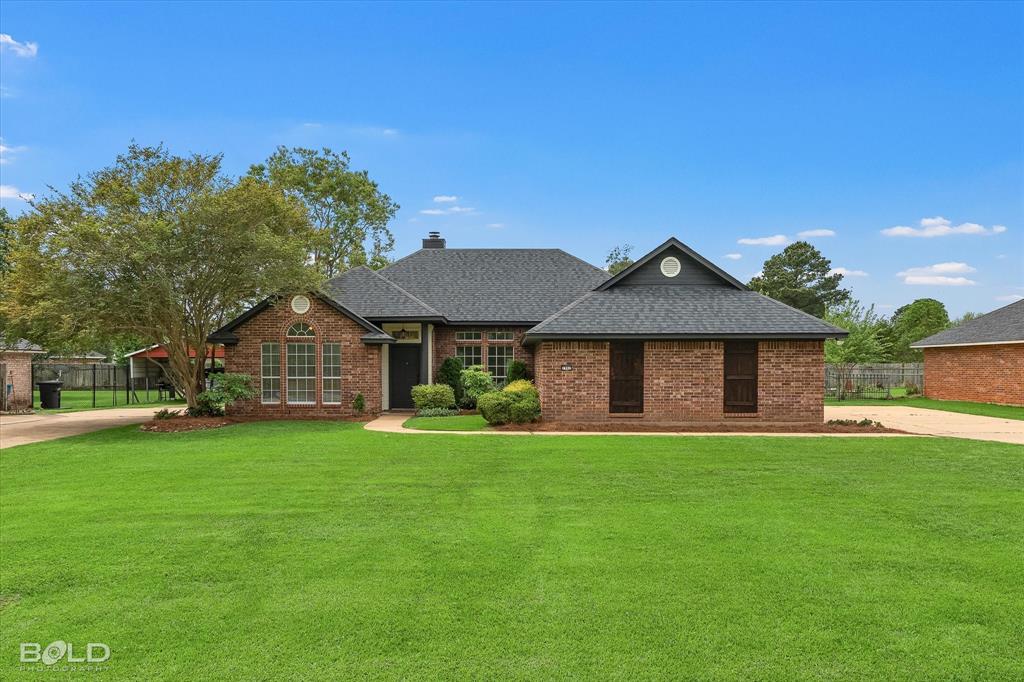 1962 Palmetto Road Benton, LA 71006 - Photo 39 of 40 The property features a brick exterior, a dark shingle roof, and a well-maintained lawn