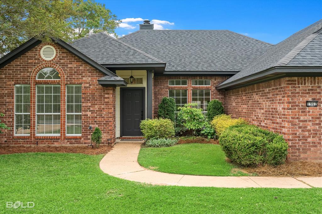 1962 Palmetto Road Benton, LA 71006 - Photo 40 of 40 The property features an attractive brick exterior, a dark gray roof, and a well-maintained lawn with mature landscaping
