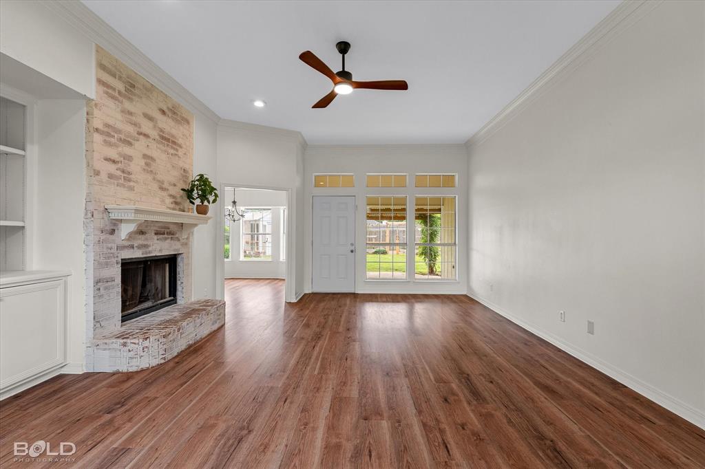 1962 Palmetto Road Benton, LA 71006 - Photo 4 of 40 Spacious living area featuring a whitewashed brick fireplace, a ceiling fan, and rich wood-toned flooring
