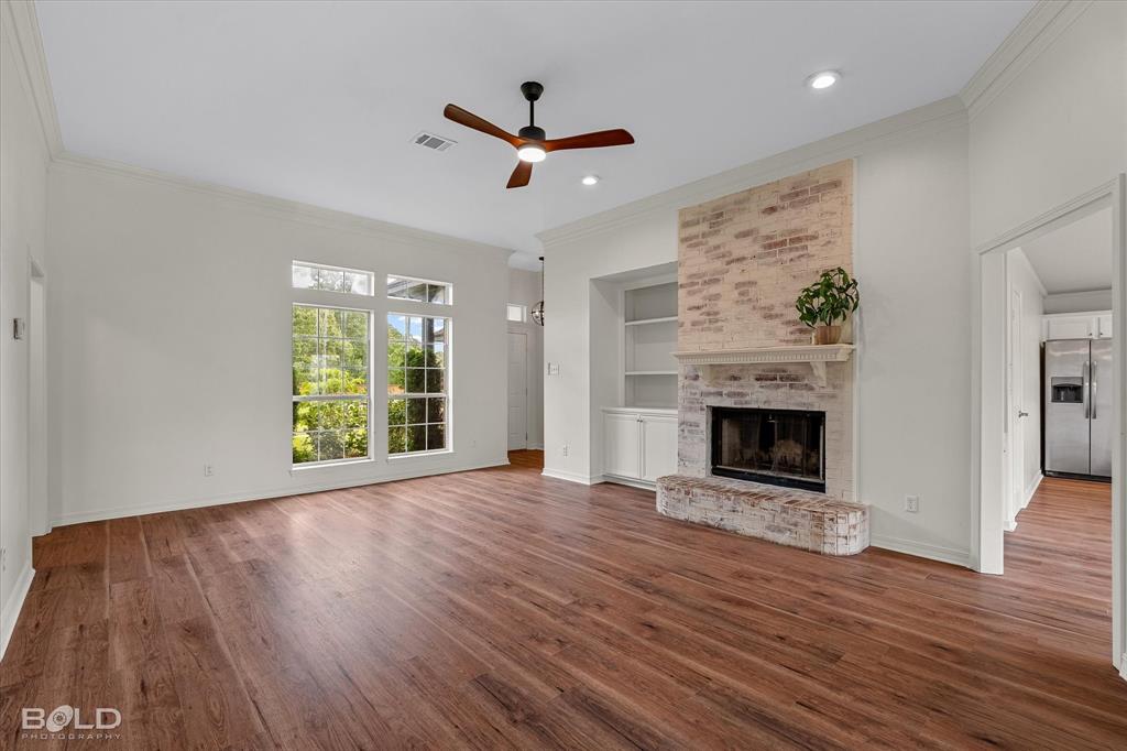 1962 Palmetto Road Benton, LA 71006 - Photo 7 of 40 Living area featuring hardwood flooring, a whitewashed brick fireplace, built-in shelving, and a ceiling fan