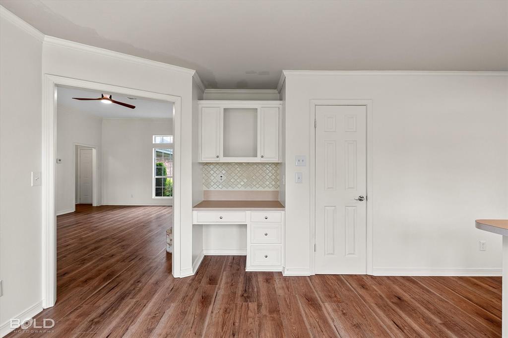 1962 Palmetto Road Benton, LA 71006 - Photo 10 of 40 This interior view features hardwood flooring, white walls, and an integrated desk area with cabinet storage and a tiled backsplash