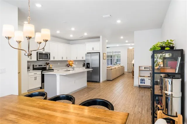 a kitchen with stainless steel appliances granite countertop a refrigerator oven a sink dishwasher and white cabinets with wooden floor