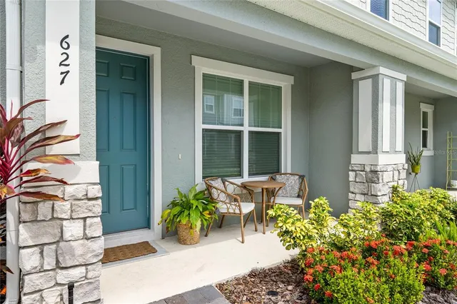 front of a brick house with potted plants and a bench