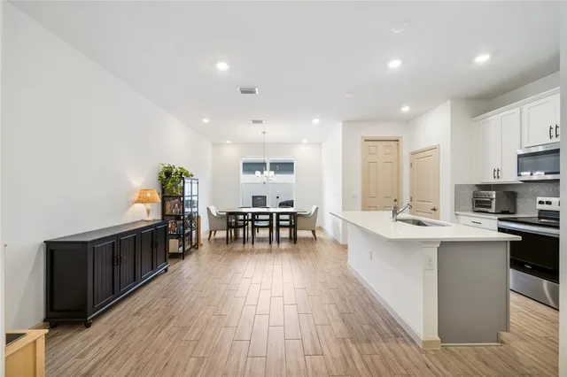a kitchen with stainless steel appliances a dining table chairs stove and white cabinets