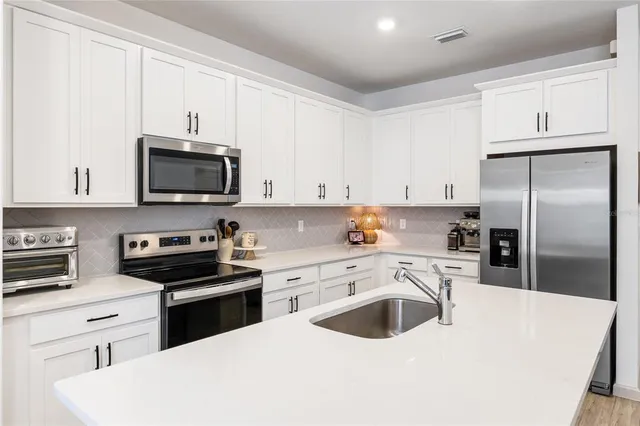 a kitchen with cabinets stainless steel appliances and a sink