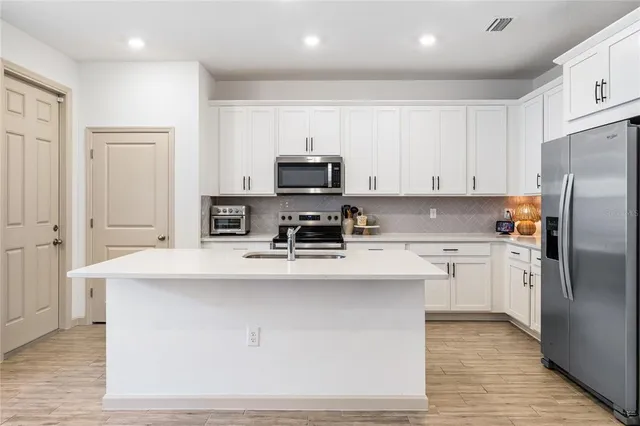 a kitchen with kitchen island white cabinets and stainless steel appliances