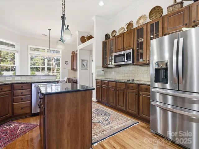 a kitchen with stainless steel appliances granite countertop a refrigerator a sink dishwasher a stove and white countertops with wooden floor