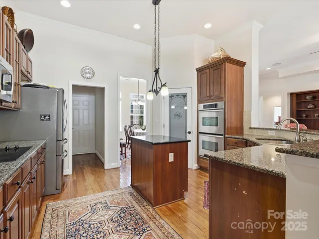 a kitchen with stainless steel appliances granite countertop a sink a stove and a refrigerator