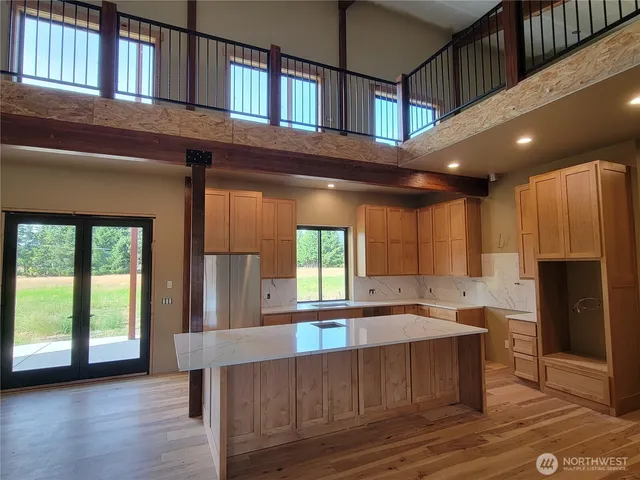 a kitchen with stainless steel appliances granite countertop a refrigerator a sink dishwasher a stove and a dining table with wooden floor