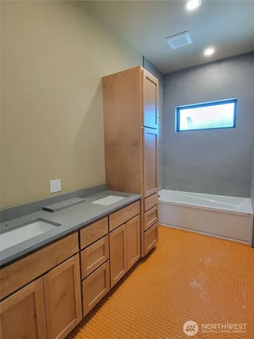 a bathroom with a granite countertop sink and a bathtub