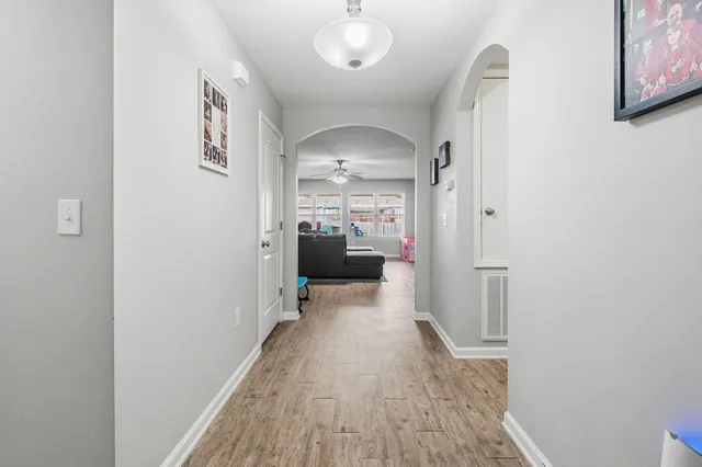 a view of a hallway with wooden floor a bathroom and a sink