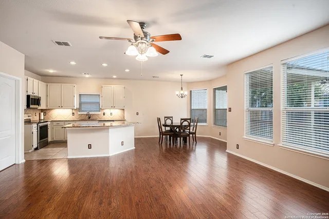 a kitchen with a white dining table chairs stove and white cabinets