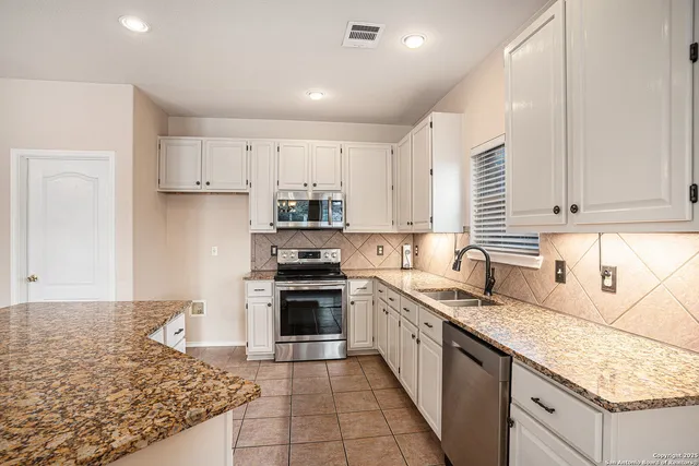 a large kitchen with granite countertop a sink stove and cabinets