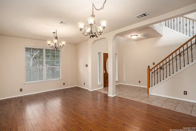 a view of an empty room with wooden floor and a chandelier