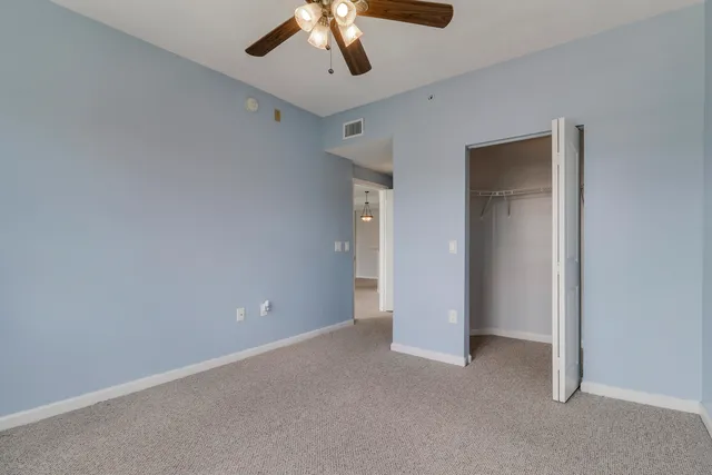 an empty room with windows and chandelier fan