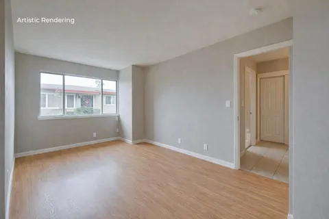 a view of an empty room with wooden floor and a window