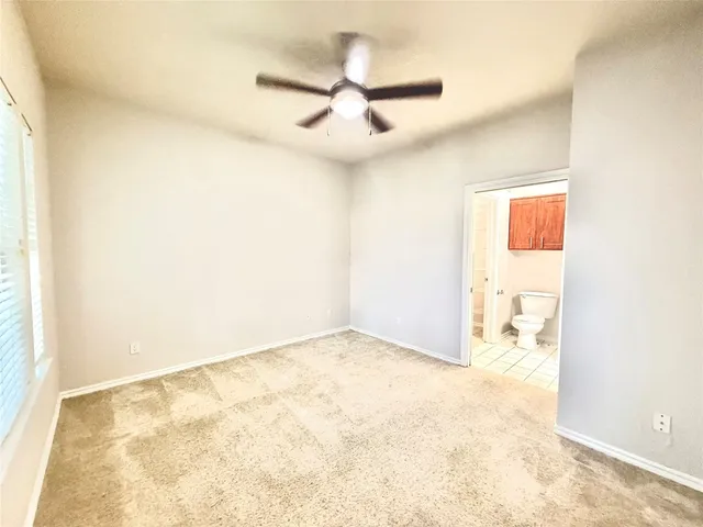 an empty room with a ceiling fan and window