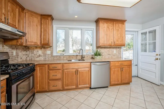 a kitchen with granite countertop cabinets stainless steel appliances a sink and a window