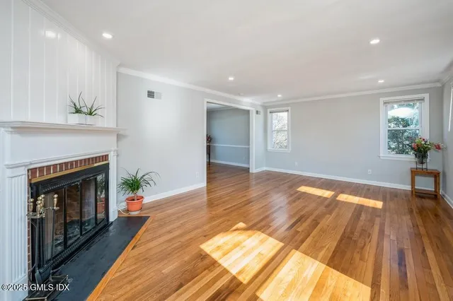a view of an empty room with wooden floor and a fireplace