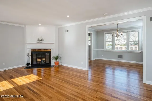 an empty room with wooden floor fireplace and windows