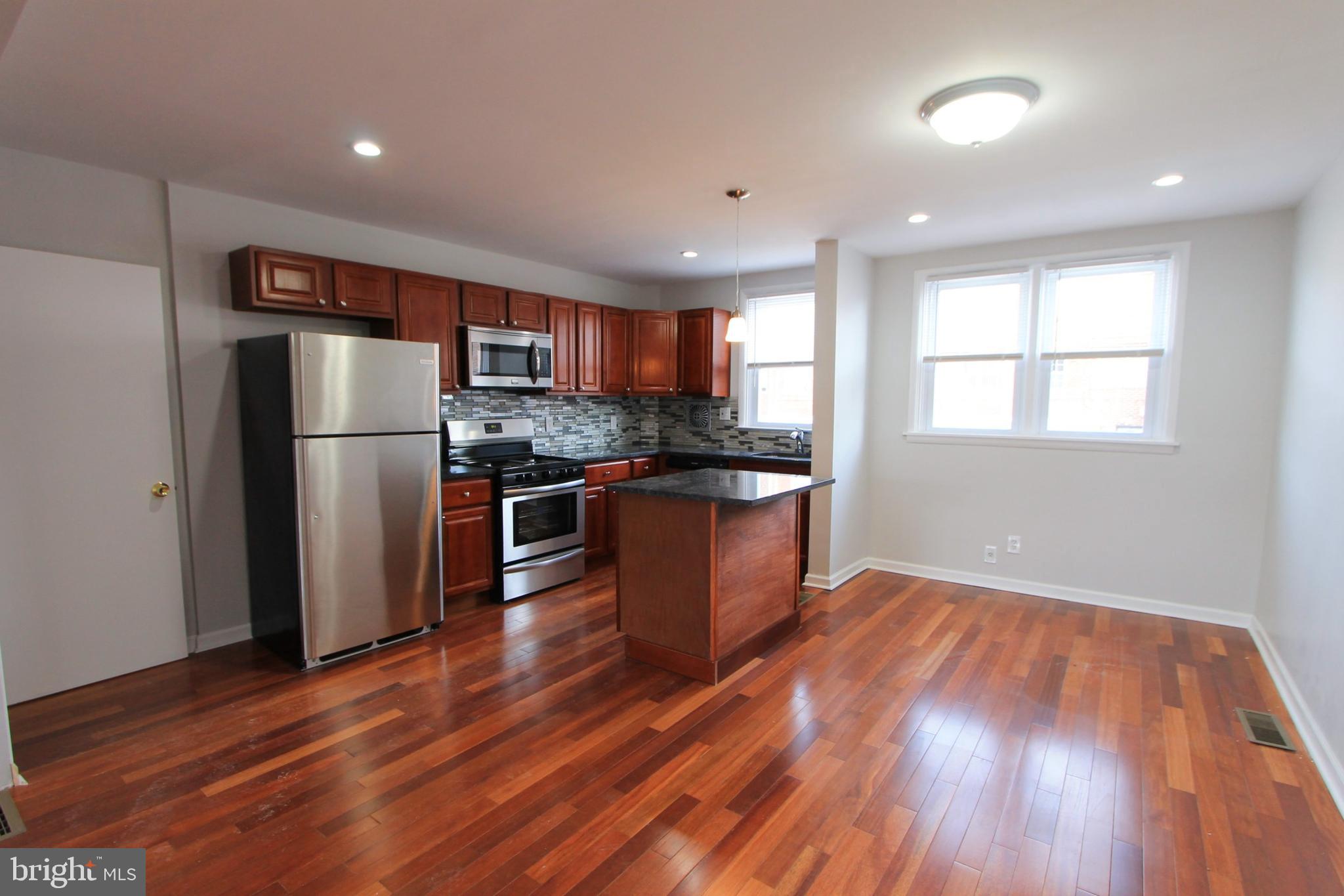 8613 Gilbert Street Philadelphia, PA 19150 - Photo 7 of 28 a kitchen with stainless steel appliances granite countertop a refrigerator a sink dishwasher a stove and white countertops with wooden floor