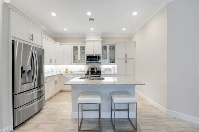a kitchen with kitchen island white cabinets and stainless steel appliances
