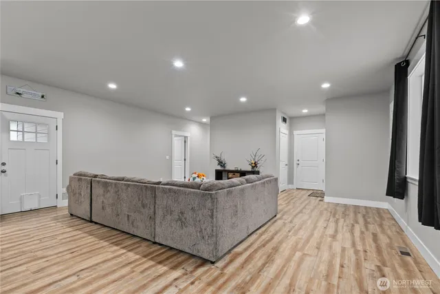 a living room with stainless steel appliances kitchen island granite countertop wooden floors and a sink
