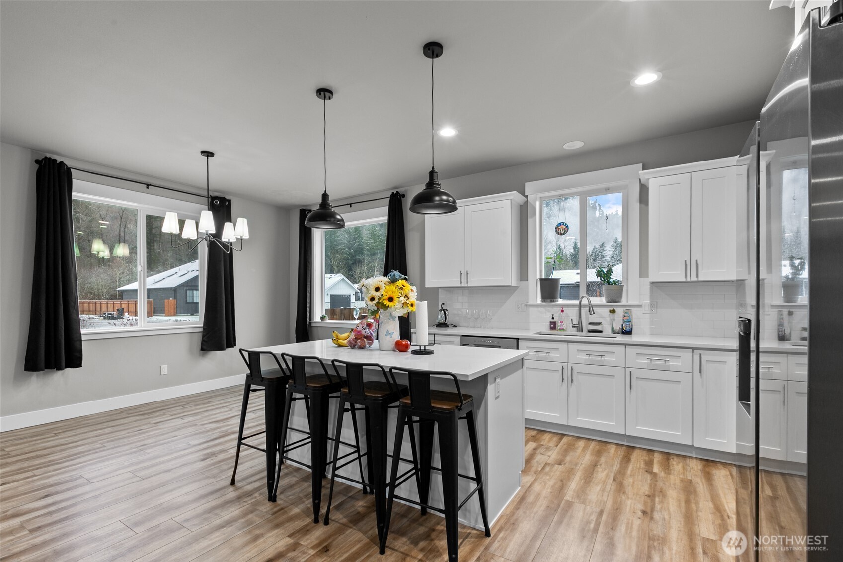 8233 Goldrun Drive Maple Falls, WA 98266 - Photo 9 of 24 a kitchen with stainless steel appliances kitchen island granite countertop a dining table chairs and white cabinets