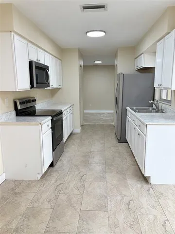 a kitchen with granite countertop a sink a stove top oven and stainless steel appliances