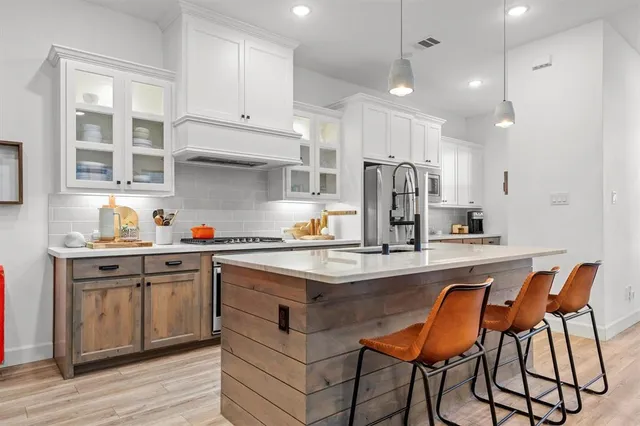 a kitchen with stainless steel appliances granite countertop a sink a stove a refrigerator and island with wooden floor