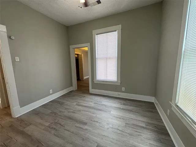 an empty room with wooden floor and windows