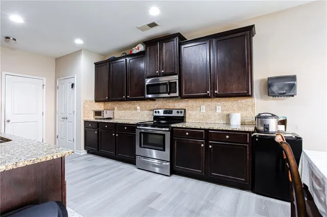 a kitchen with granite countertop wooden cabinets and black stainless steel appliances