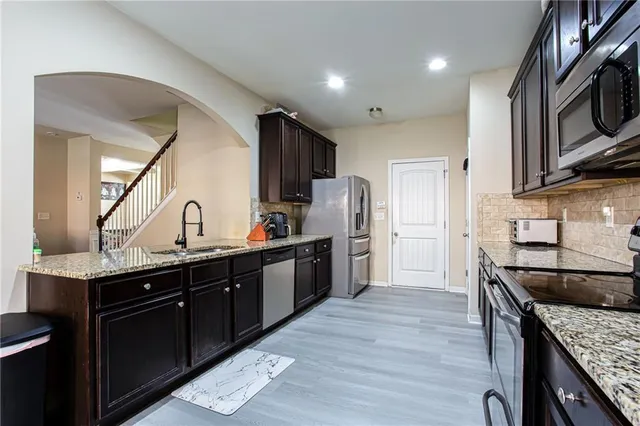 a kitchen with stainless steel appliances granite countertop a sink stove and refrigerator
