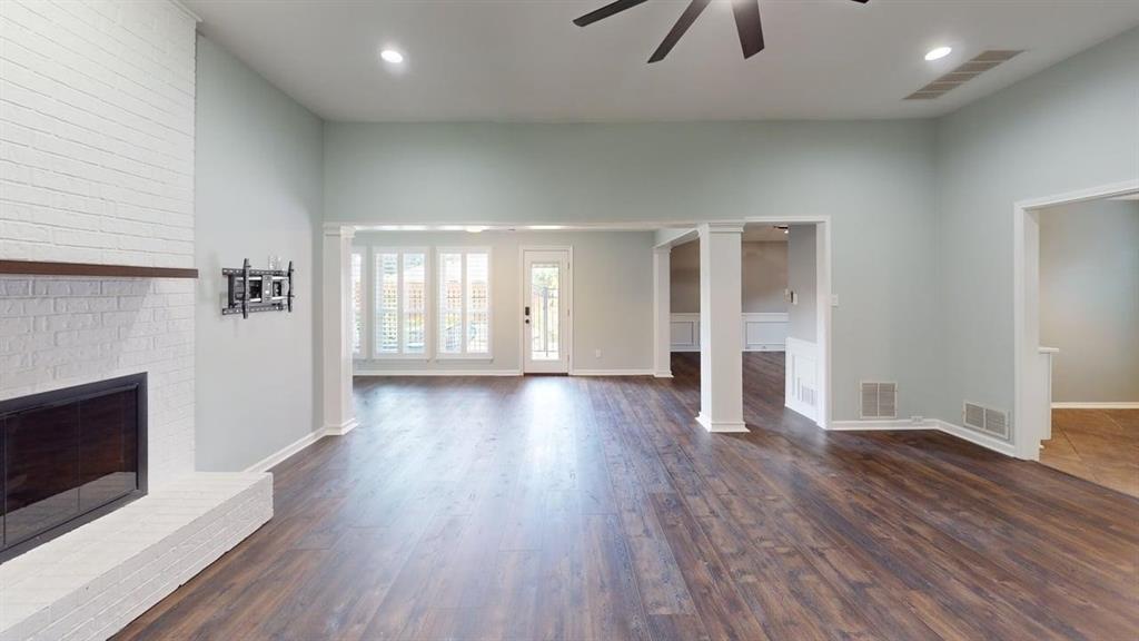 Spacious room with wood-finish flooring, a white brick fireplace, recessed lighting, and a ceiling fan
