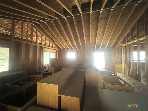 a view of an empty room with wooden floor and windows