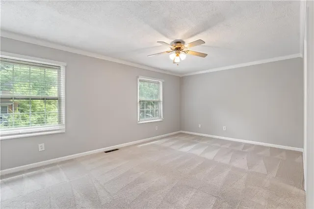 an empty room with windows and chandelier fan