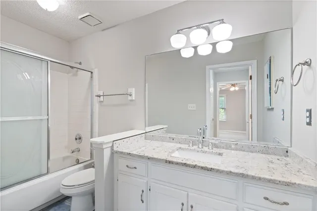 a bathroom with a granite countertop sink a toilet and a large mirror