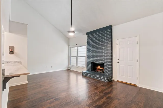 a view of an empty room with wooden floor fireplace and a window