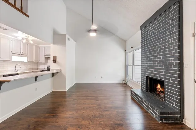 a open kitchen with granite countertop a stove top oven a sink dishwasher and a fireplace with wooden floor