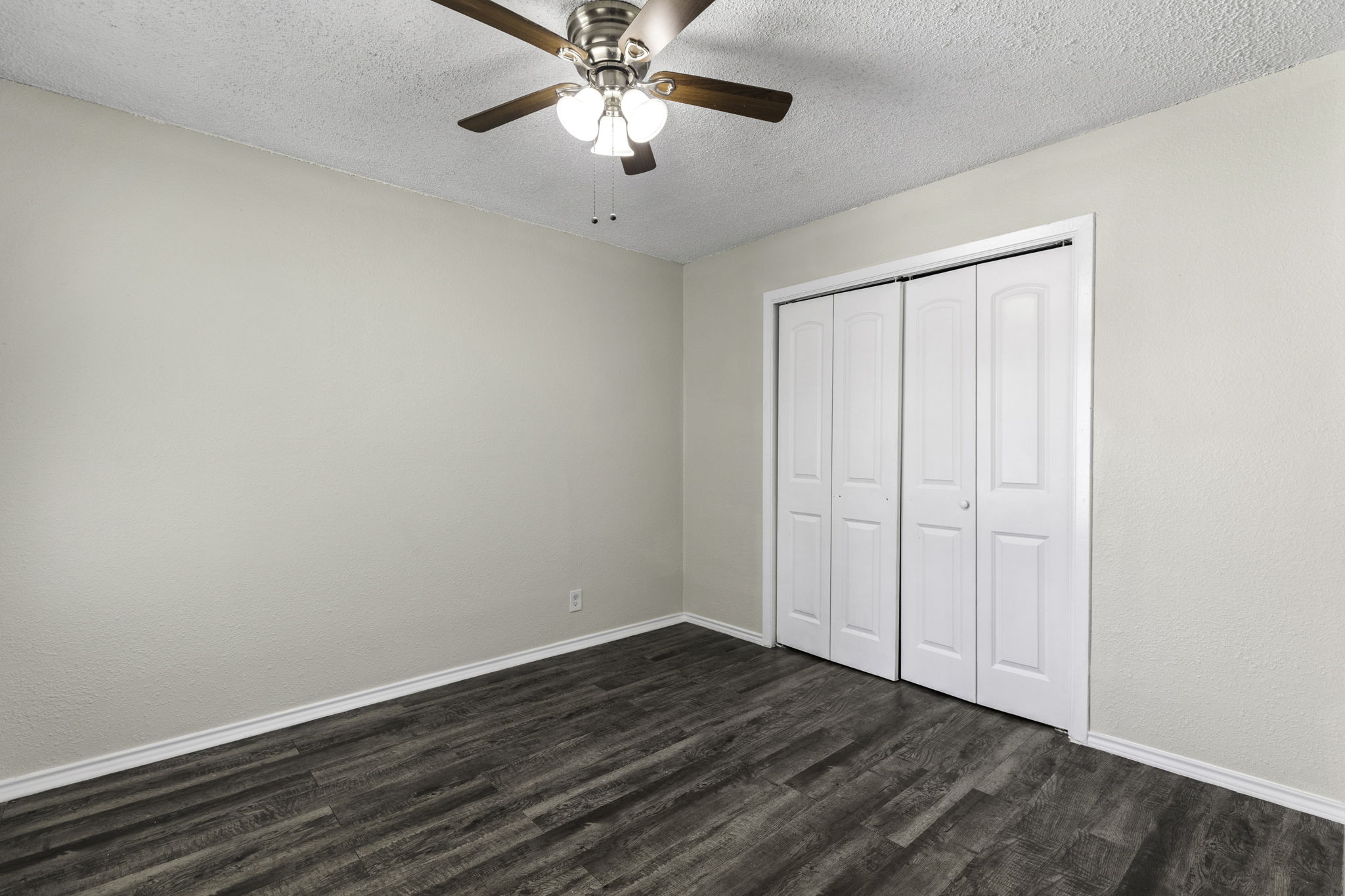 6110 Wheless Cove, Unit E Austin, TX 78723 - Photo 12 of 15 Unfurnished bedroom featuring dark wood-style floors, a ceiling fan, a textured ceiling, and a closet