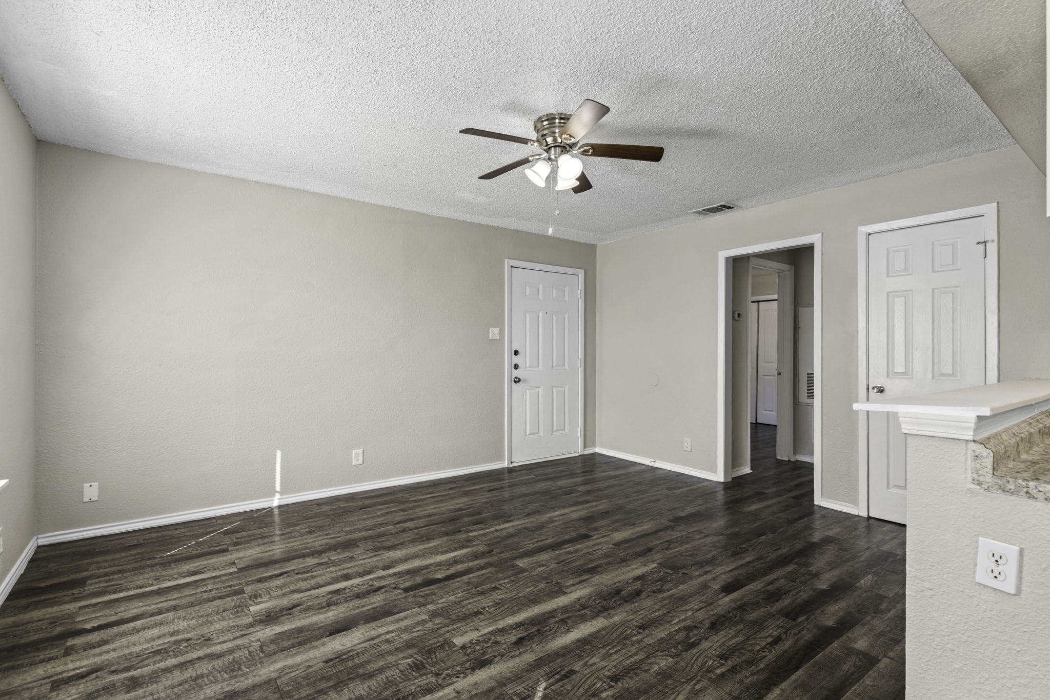 6110 Wheless Cove, Unit E Austin, TX 78723 - Photo 4 of 15 Unfurnished living room with a textured ceiling, dark wood-style floors, and a ceiling fan