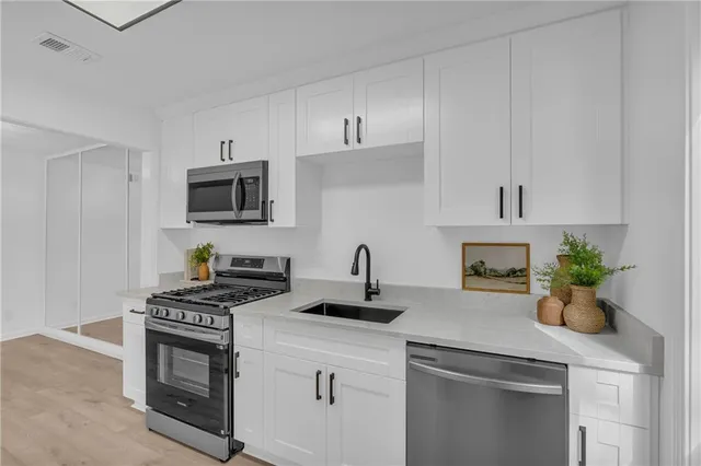 a kitchen with stainless steel appliances a stove a sink a microwave and cabinets
