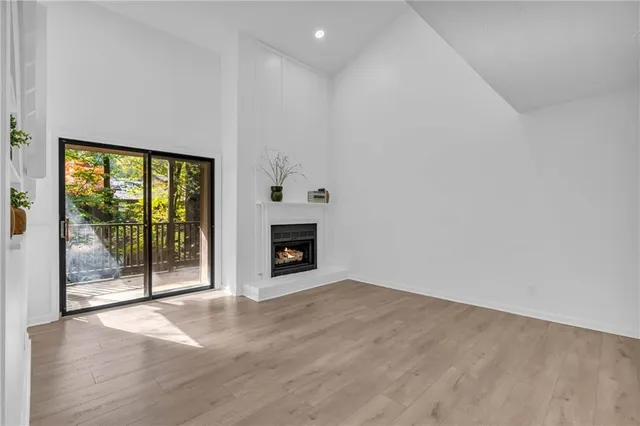 a view of an empty room with wooden floor and a fireplace