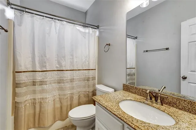 a bathroom with a granite countertop sink toilet and shower