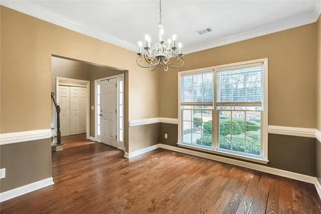 a view of an empty room with window wooden floor and a kitchen