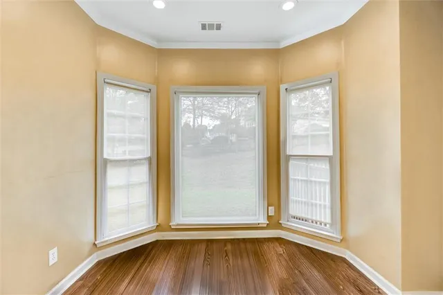 an empty room with wooden floor and windows
