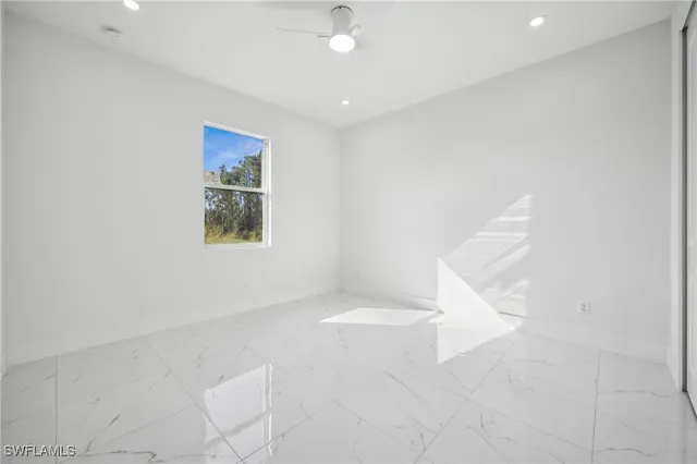 an empty room with a ceiling fan and windows
